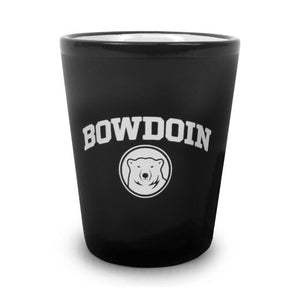 Matte black shot glass with white interior and white imprint of BOWDOIN arched over a polar bear medallion.