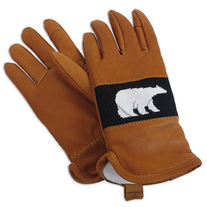 Photo of tan leather gloves with a needlepointed panel on the back of the hand depicting a white polar bear on a black background. The gloves have a plush white fleece lining and a pull-on tab at the wrist with the logo SMATHERS & BRANSON imprinted on the tab.