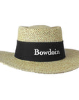 Tan straw sun hat with black band with embroidered BOWDOIN wordmark on front.