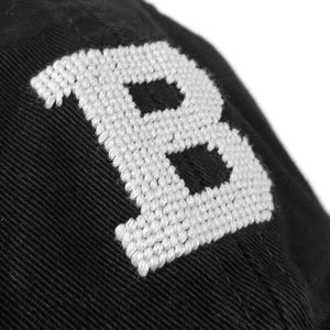 Closeup view of needlepointing on black hat.