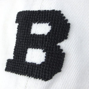 Closeup view of needlepointing on white hat.