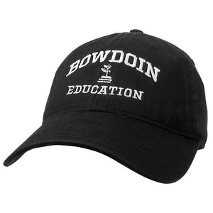Black ball cap with white embroidery of BOWDOIN arched over a plant growing out of a stack of books over EDUCATION