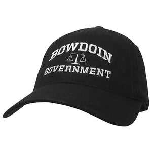 Black ball cap with white embroidery of BOWDOIN arched over a scale over GOVERNMENT