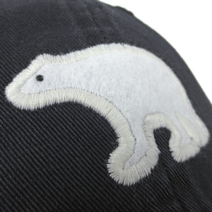 Closeup of white felt polar bear applique on black baseball hat.