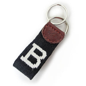 Needlepointed keyfob decorated with a white Bowdoin B on a black background. Small leather tab at the end attaching the metal key ring, debossed with the S&B logo.