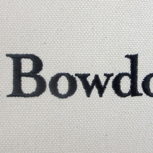 Closeup of the letters BOWD embroidered in black on natural canvas.