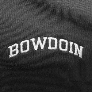 Closeup of white arched BOWDOIN embroidery on black polo shirt.