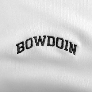 Closeup of black arched BOWDOIN embroidery on white polo shirt.