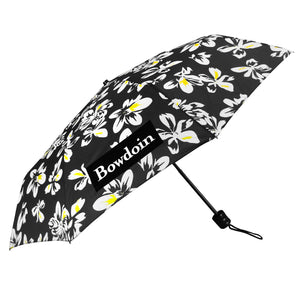 Black umbrella with white and yellow hibiscus floral print all over, and rectangular BOWDOIN wordmark imprint.